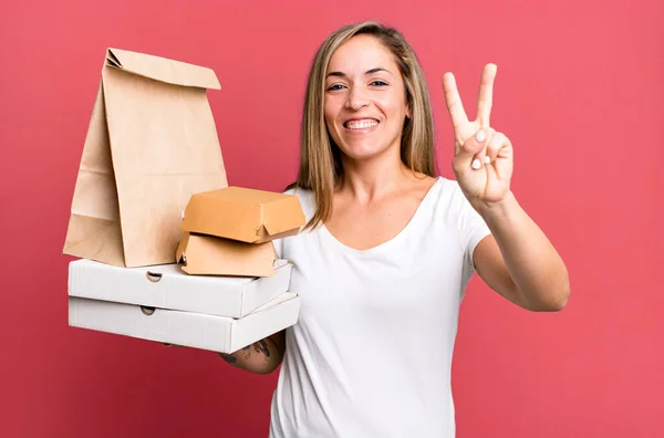 かなりブロンドの女性は笑顔で友好的に見える2番目を示しています 配送は食品パッケージの概念を取り除き — ストック写真