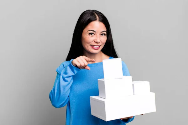 ヒスパニック系のかなりの女性が陽気に笑顔 幸せと側を指して感じている 白い箱の包装で — ストック写真