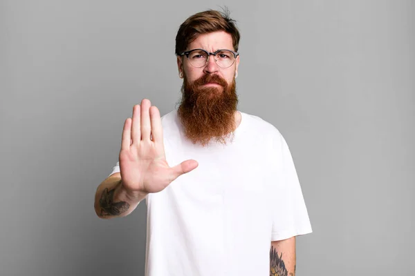 Długa Broda Rude Włosy Człowiek Wygląda Poważnie Pokazując Otwartą Dłoń — Zdjęcie stockowe