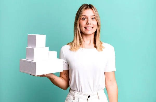 stock image young pretty woman looking happy and pleasantly surprised. blank white boxes concept