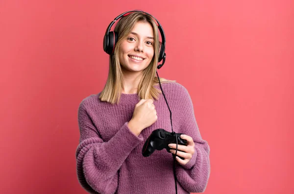 Stock image young pretty woman feeling happy and facing a challenge or celebrating. gamer with headset and controller