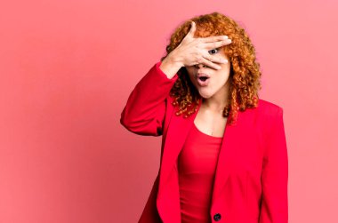 Kızıl saçlı, güzel bir kadın şok olmuş, korkmuş ya da korkmuş görünüyor, yüzünü elleriyle kapatıyor. İş kadını kavramı