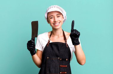 Gülümsüyor ve dost canlısı görünüyor, bir numarayı gösteriyor. Kasap konsepti