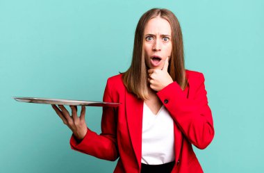 Ağzı ve gözleri açık ve elleri çenesinde. İş kadını tepsiyle sunum yapıyor.