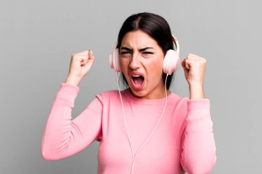 Kızgın bir ifadeyle agresif bir şekilde bağırıyordu. kulaklıkla müzik dinlemek