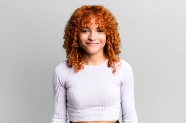 kızıl saçlı güzel kadın pozitif ve kendinden emin gülümsüyor. Tatmin olmuş, arkadaş canlısı ve mutlu görünüyor.