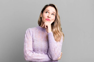 Yoğunlaşmış bir bakışla, şüpheli bir ifadeyle, yukarı ve yana bakarak