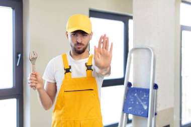 Genç ve yakışıklı adam ciddi görünüyor. Avuç içi gösteriyor. Durdurma hareketi yapıyor. Becerikli adam kavramı