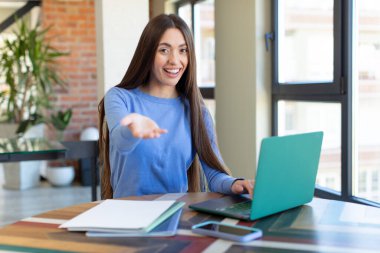 Mutlu bir şekilde gülümsemek ve bir konsept sunmak veya göstermek. dizüstü bilgisayar ve masa konsepti