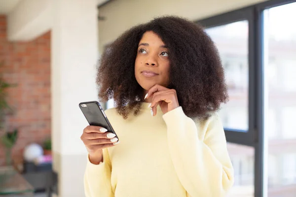 stock image pretty afro black woman smiling with a happy, confident expression with hand on chin. smartphone concept