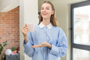 Neşeli bir şekilde gülümsemek, mutlu olmak ve bir konsept göstermek. Evde kahve fincanı var. kahve fincanı evde.