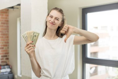 Çapraz hissetmek, baş parmakları aşağı göstermek. Dolar banknotları konsepti