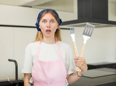 Genç ve güzel bir kadın şok olmuş ve şaşırmış hissediyor. ev aşçısı konsepti