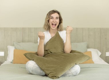 Güzel kadın şokta, gülüyor ve başarıyı kutluyor. Gece elbisesi ve yatak odası konsepti