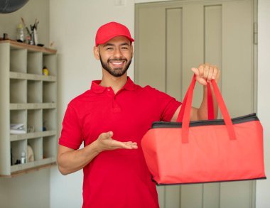 Genç yetişkin bir adam neşeyle gülümser, mutlu hisseder ve bir konsept gösterir. Pizza teslimatçısı konsepti