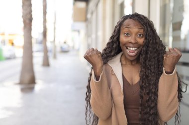 Afro güzel siyah kadın şok olmuş, heyecanlı ve mutlu hissediyor, gülüyor ve başarıyı kutluyor,!