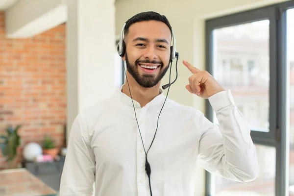 stock image young  adult man smiling cheerfully, feeling happy and showing a concept. telemarketer concept