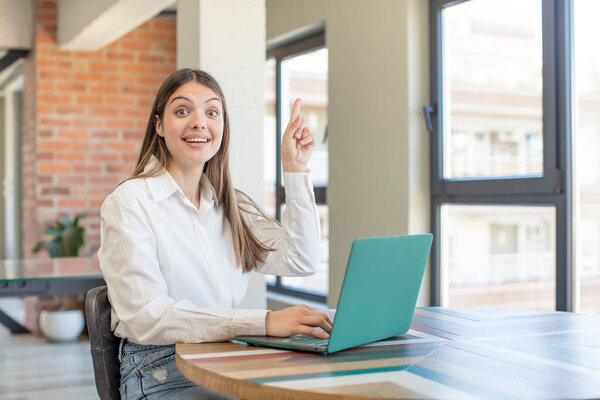 молодая красивая женщина чувствует себя счастливым и взволнованным гением после реализации идеи. работа с ноутбуком