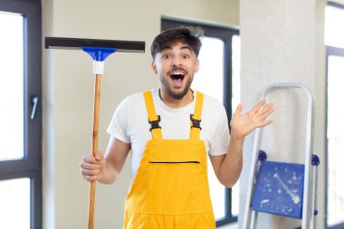 Genç yakışıklı adam kendini mutlu hissediyor ve inanılmaz bir şeye hayret ediyor. pencere temizleme konsepti