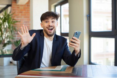 Genç yakışıklı adam kendini mutlu hissediyor ve inanılmaz bir şeye hayret ediyor. akıllı telefon kavramı