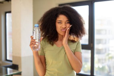 Oldukça afro siyah bir kadın bıkkın, hayal kırıklığına uğramış ve yorucu bir günün ardından uykulu hissediyor. su şişesi kavramı