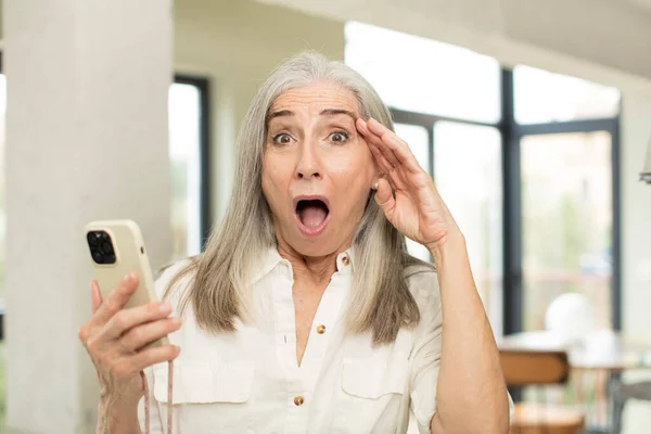 幸せそうな年配の女性は驚き驚きました スマートフォンのコンセプト — ストック写真