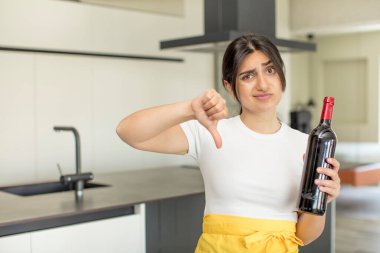 Genç bir kadın kendini kötü hissediyor, baş parmağını kaldırıyor. şarap şişesi konsepti