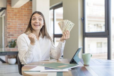 Genç ve güzel bir kadın şokta, gülüyor ve başarıyı kutluyor. Evden işe dolaşma kavramı