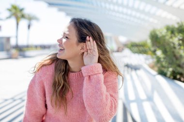 Güzel İspanyol kadın mutlu görünüyor, dinliyor, gizli bir konuşma veya dedikodu duymaya çalışıyor, kulak misafiri oluyor.
