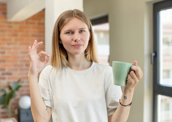 若い女性は喜んでいます良いジェスチャーで承認を示します コーヒーカップのコンセプト — ストック写真