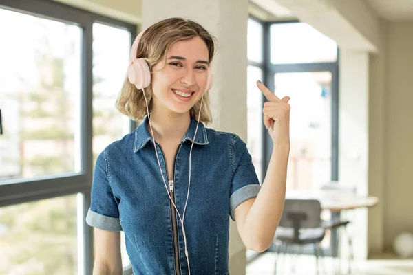 Güzel bir kadın neşeyle gülümser, mutlu hisseder ve bir konsept gösterir. kulaklıklar ve müzik konsepti