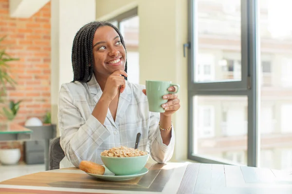 black afro woman smiling with a happy, confident expression with hand on chin. breakfast concept