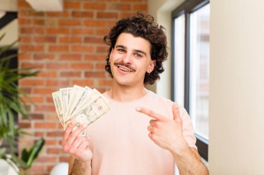 İç mekanında dolar banknotları olan genç yakışıklı bir adam.