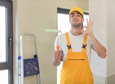 Genç yakışıklı adam kendini mutlu hissediyor, iyi bir jestle onaylıyor. resim ev kavramı