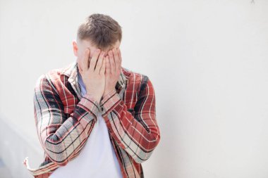 Yakışıklı adam üzgün, hayal kırıklığına uğramış, gergin ve depresif, iki eliyle yüzünü kaplayan, ağlayan