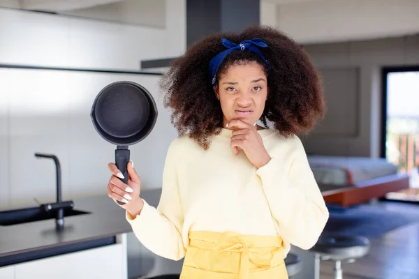 stock image pretty afro black woman with mouth and eyes wide open and hand on chin. home chef concept