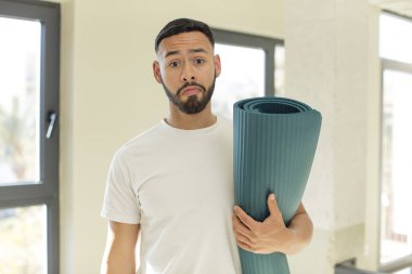 Arap yakışıklı adam, üzgün ve mızmız, mutsuz bakışlı ve ağlayan. yoga mat konsepti