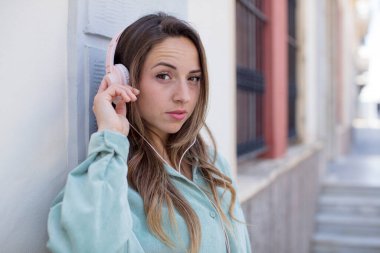 Güzel bir kadın gülümsüyor ve mutlu ve kendinden emin bir ifadeyle bakıyor. kulaklıklar ve müzik konsepti