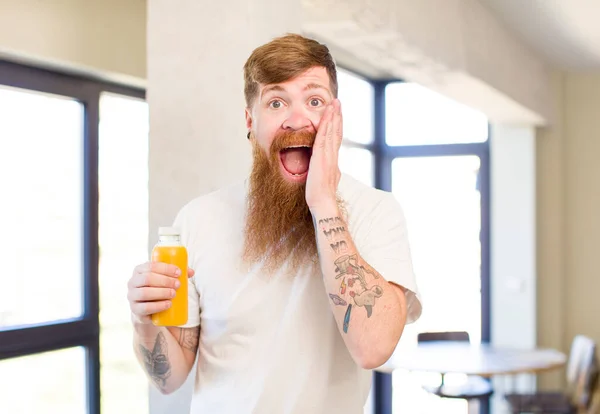 红头发的男人对橘子汁瓶令人难以置信的东西感到欣慰和惊讶 — 图库照片