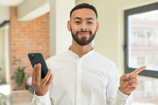 Young Adult Man Smiling Cheerfully Feeling Happy Pointing Side Smartphone — Stock Photo, Image