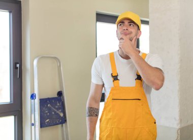 Genç ve yakışıklı bir adam mutlu ve kendinden emin bir ifadeyle gülümsüyor, elleri çenesinde. Becerikli adam kavramı