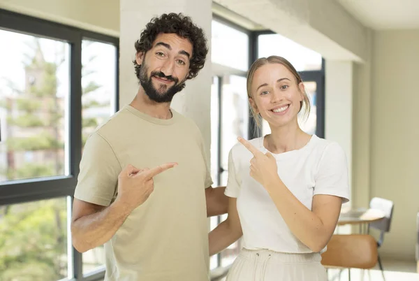Young Adult Couple Smiling Cheerfully Feeling Happy Pointing Side Upwards — Stock Photo, Image