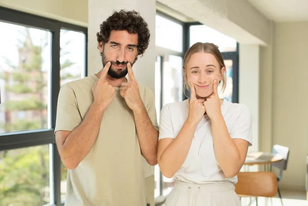 Young Adult Couple Smiling Confidently Pointing Own Fake Smile — Stock Photo, Image