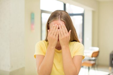 Güzel sarışın bir kadın üzgün, hayal kırıklığına uğramış, gergin ve depresif, iki eliyle yüzünü kaplayan, ağlayan