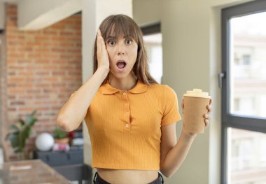 Genç ve güzel bir kadın şok olmuş ve şaşırmış hissediyor. kahve konseptini kaldır.