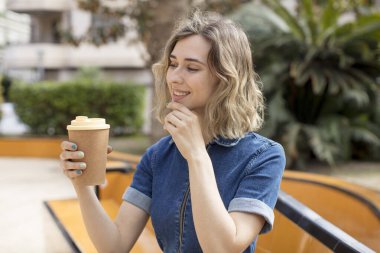 pretty woman smiling with a happy, confident expression with hand on chin. take away coffee concept
