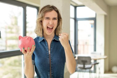 Güzel bir kadın sinirli, sinirli ve sinirli görünüyor. Domuz kumbarası konsepti