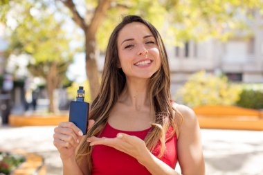 Güzel bir kadın neşeyle gülümser, mutlu hisseder ve bir konsept gösterir. vaper konsepti