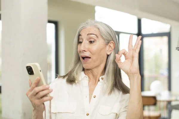 漂亮的老年妇女感到快乐 以好的姿态表示赞同 智能手机的概念 — 图库照片