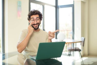 Dizüstü bilgisayarı olan sakallı genç bir adam bir şeye bakıyor, izliyor, tetikte ve tetikte bekliyor.